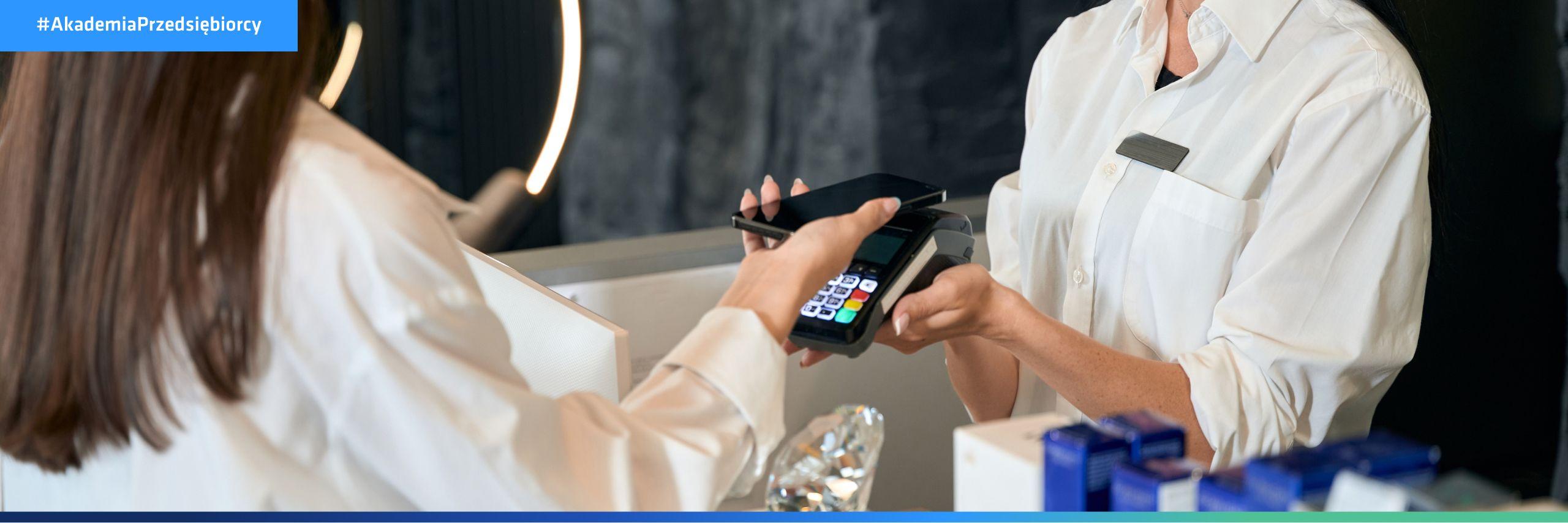 Kobieta płaci telefonem za usługę – sposób na niższe koszty prowadzenia salonu