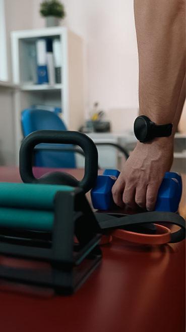 Sprzęt do ćwiczeń – kettlebell, hantle i taśmy oporowe na biurku w gabinecie fizjoterapeutycznym