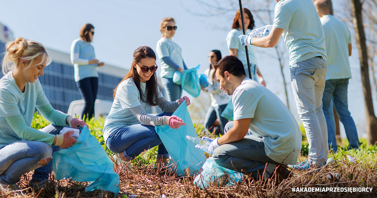 Młodzi wolontariusze zbierają śmieci z trawnika
